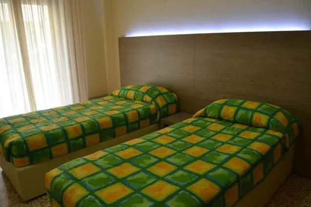 Deux lits simples dans une chambre lumineuse avec des couvertures à motifs.