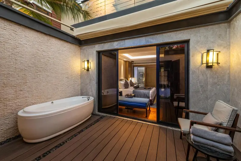 Une baignoire extérieure donne sur une chambre lumineuse et un espace détente.