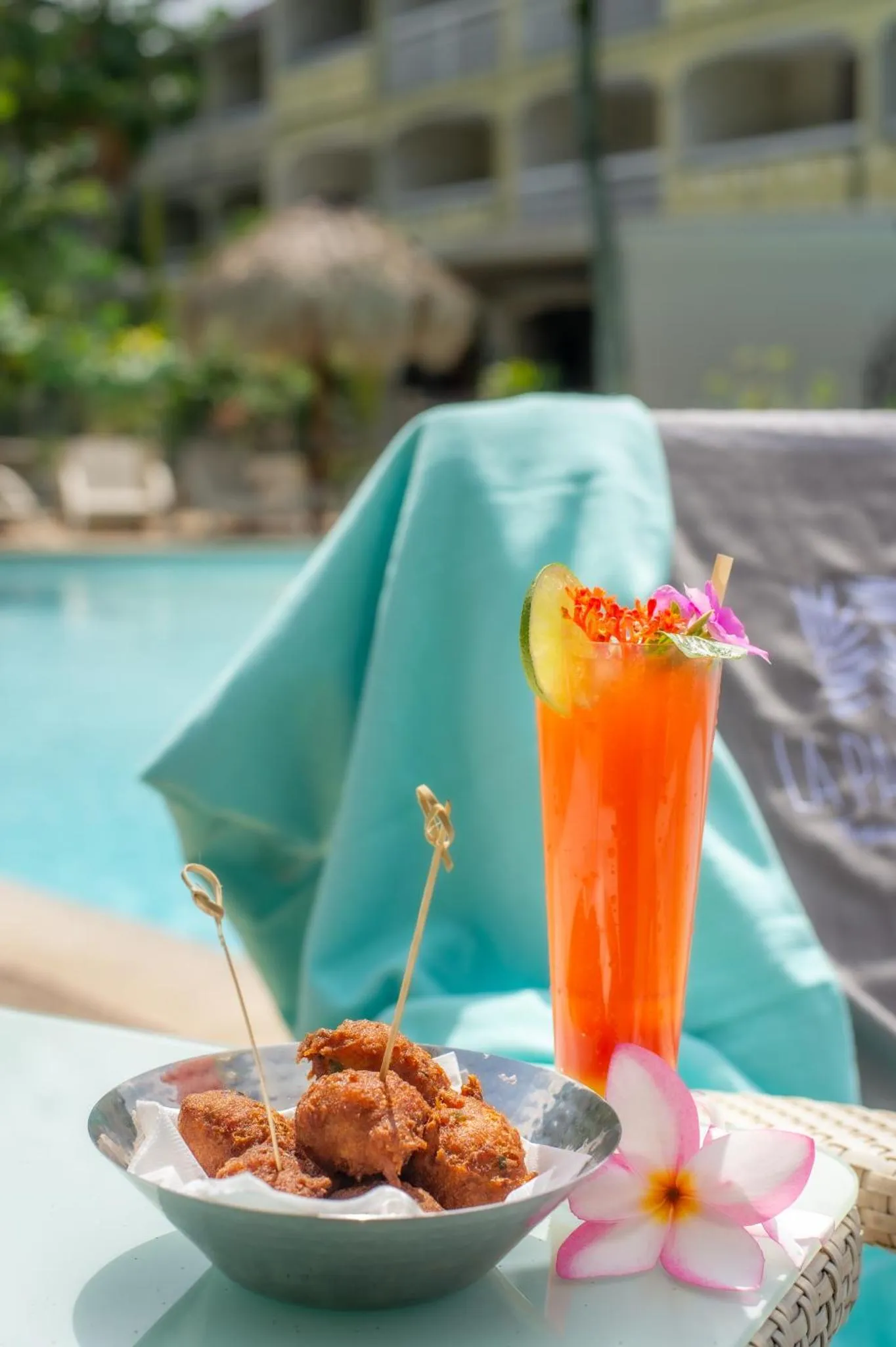 Un cocktail coloré et des amuse-gueules sont présentés au bord d'une piscine.