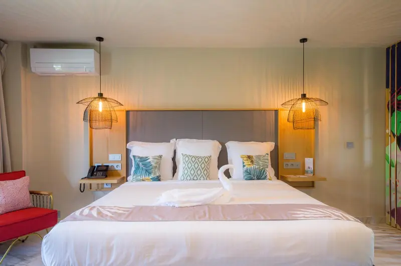 Une chambre lumineuse avec un grand lit décoré de coussins.