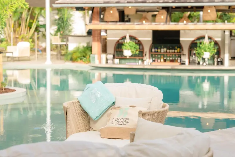 Transats et serviettes enroulées au bord d'une piscine turquoise.