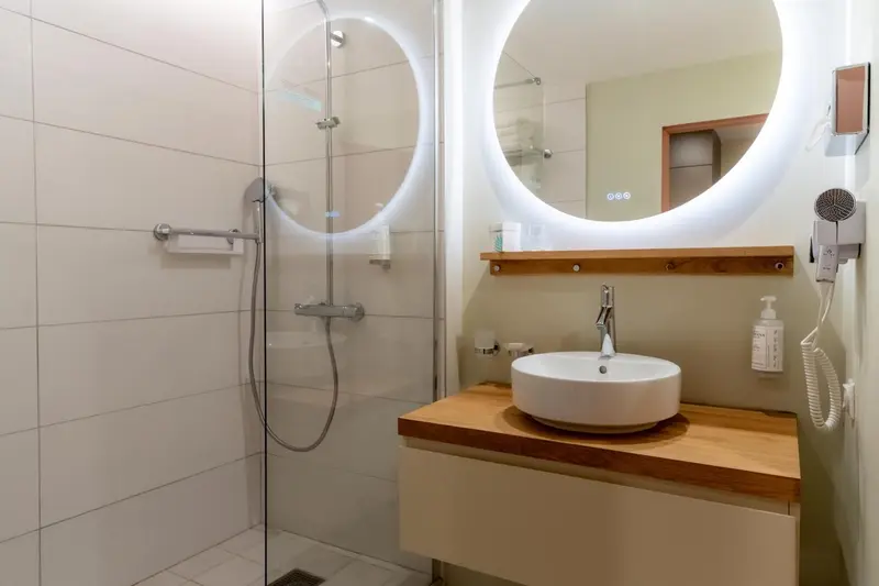 Une salle de bain moderne avec douche à l'italienne et grand miroir lumineux.