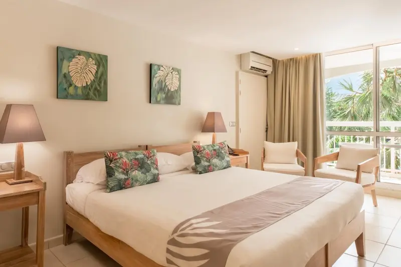 Une chambre lumineuse avec un grand lit et un coin salon.
