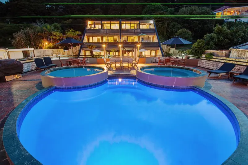 Bâtiment éclairé avec piscine et mobilier de jardin.