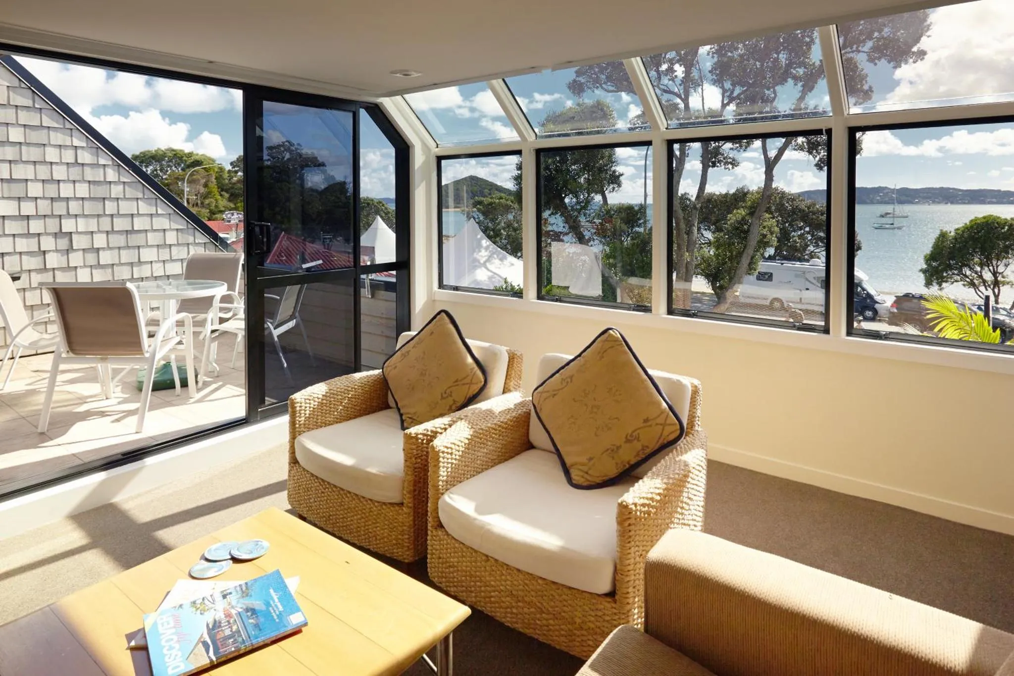 Espace de détente lumineux avec vue sur la mer et mobilier en rotin.