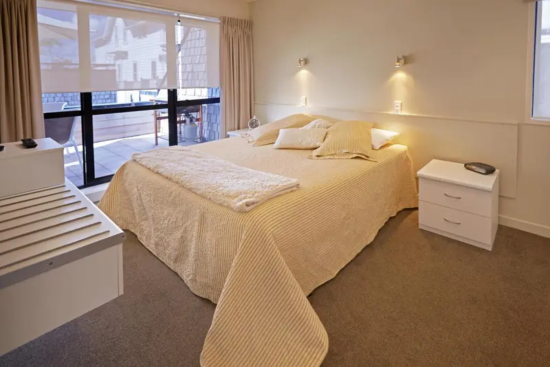 Une chambre lumineuse avec un grand lit recouvert d'une courtepointe.
