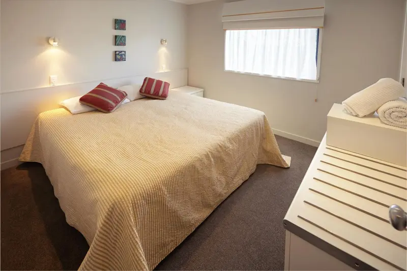 Une chambre lumineuse avec un grand lit recouvert d'une courtepointe.