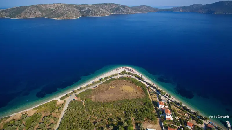 Vue aérienne d'une presqu'île rocheuse bordée d'une plage de sable et de végétation.