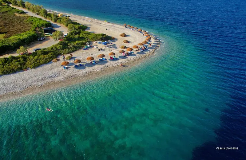Vue aérienne d'une plage de galets avec des transats et des parasols.