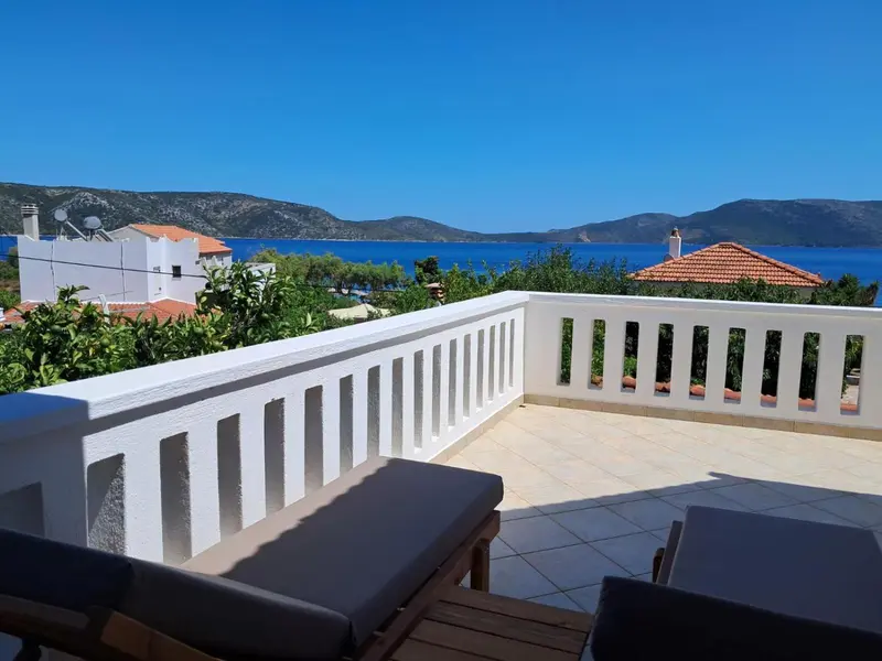 Terrasse ensoleillée avec vue sur la mer et les collines.