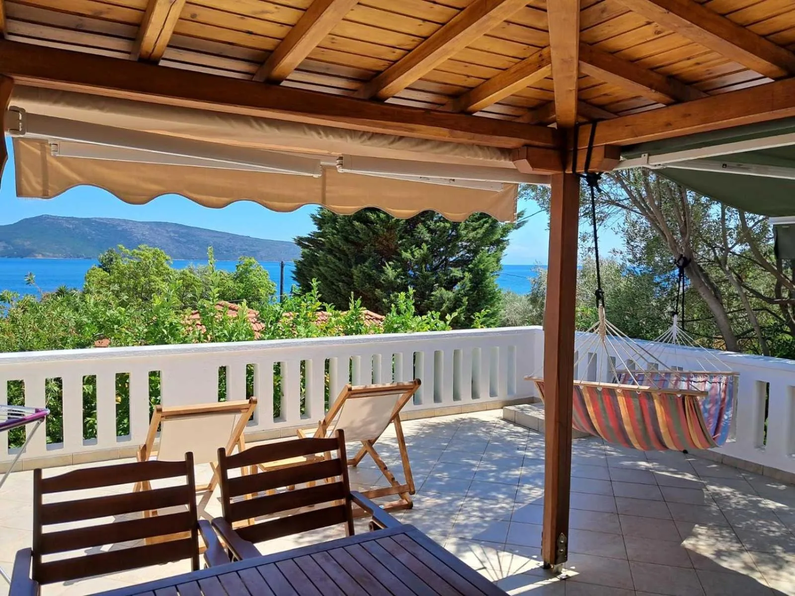 Espace extérieur ombragé avec mobilier de jardin et vue sur la mer.