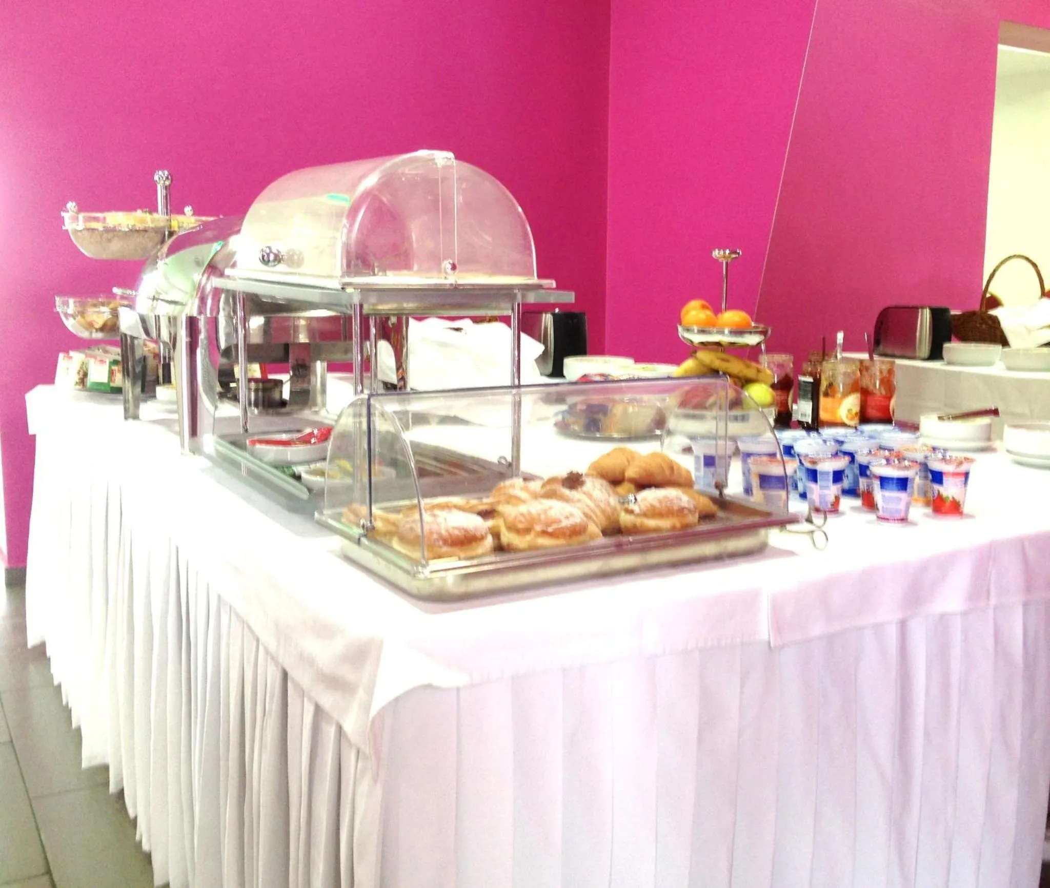 Un buffet propose des viennoiseries, des fruits et des boissons.