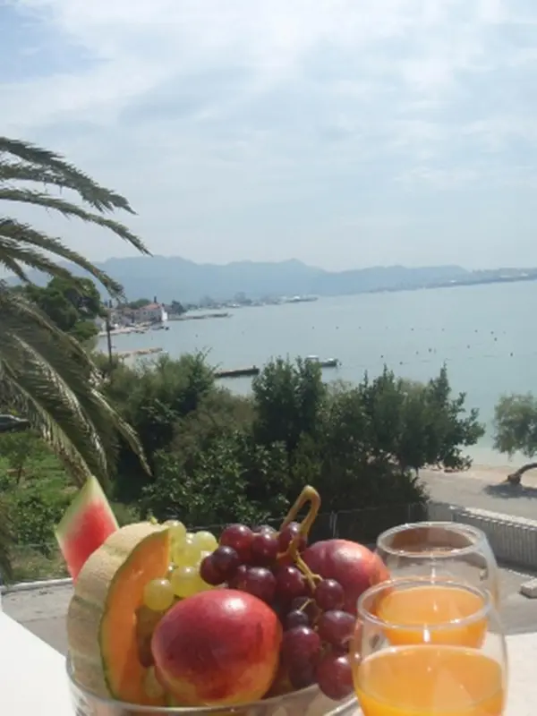 Nature morte de fruits frais et de jus sur une terrasse avec vue sur la mer.
