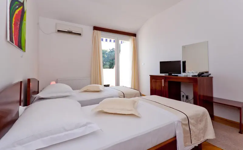 Une chambre lumineuse avec deux lits simples et un bureau.