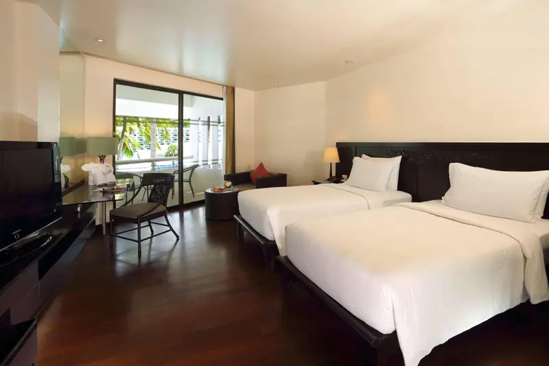 Une chambre lumineuse avec deux lits simples et un espace détente.