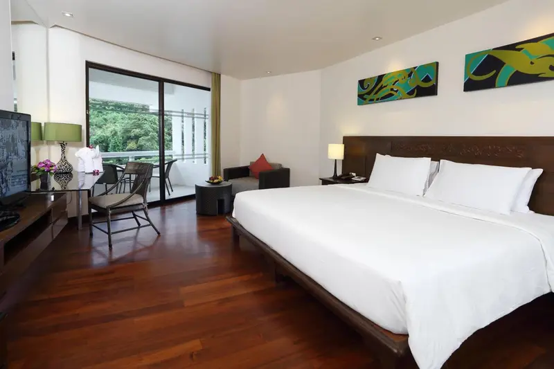 Une chambre lumineuse avec un grand lit et un coin salon donnant sur une terrasse.