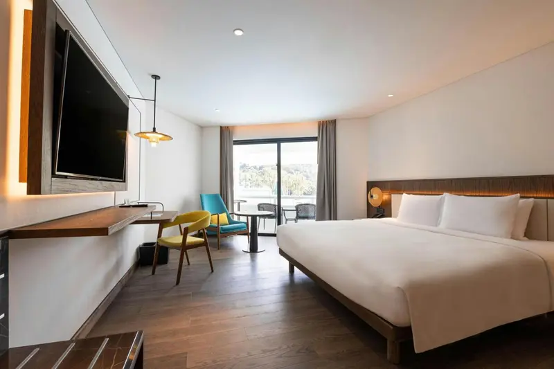 Une chambre lumineuse avec un lit double et un coin salon.