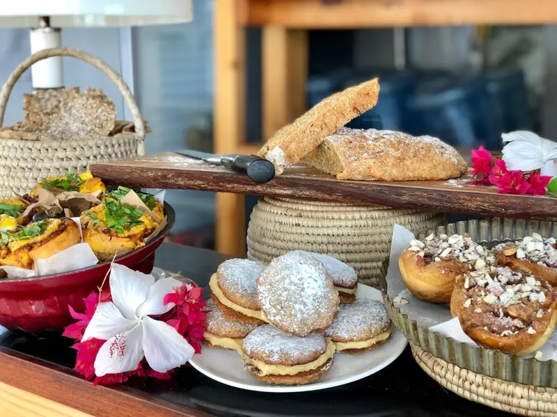 Présentation de pâtisseries et de pains sur un buffet décoré de fleurs.