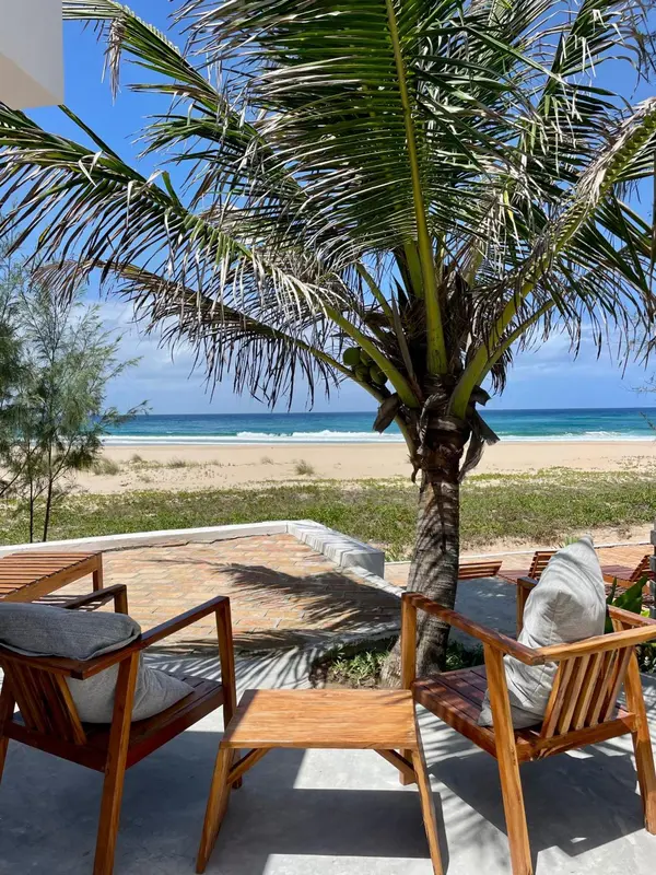 Deux fauteuils en bois sur une terrasse ensoleillée face à la mer.