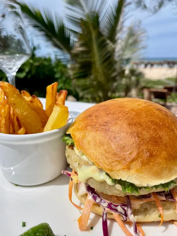 Un hamburger garni et des frites sont servis sur une table en extérieur.