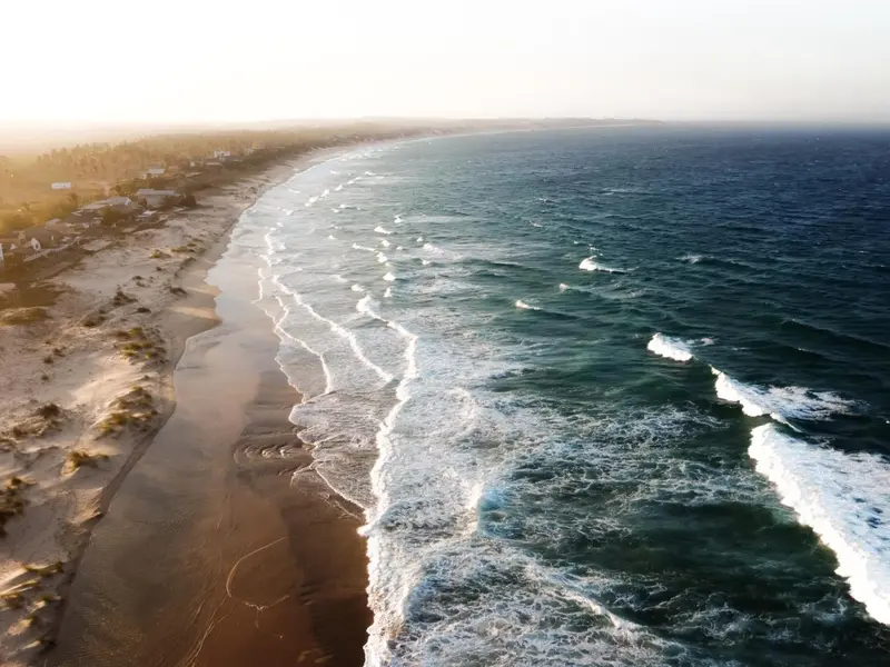 Longue plage de sable bordée par les vagues de l'océan.
