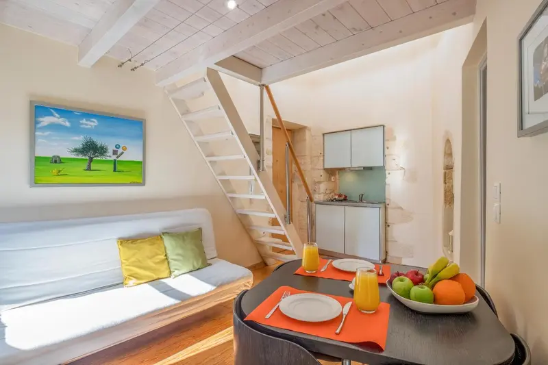 Une pièce lumineuse avec un canapé, une table et une kitchenette.