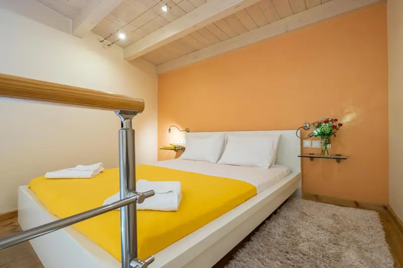 Une chambre lumineuse avec un lit recouvert d'une couverture jaune et des oreillers blancs.