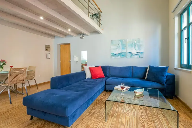 Un espace de vie lumineux avec un canapé bleu et une table basse en verre.