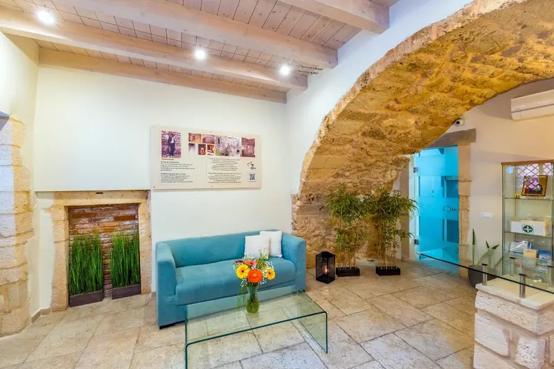 Un canapé bleu turquoise et une table basse en verre se trouvent dans un espace intérieur à murs de pierre.