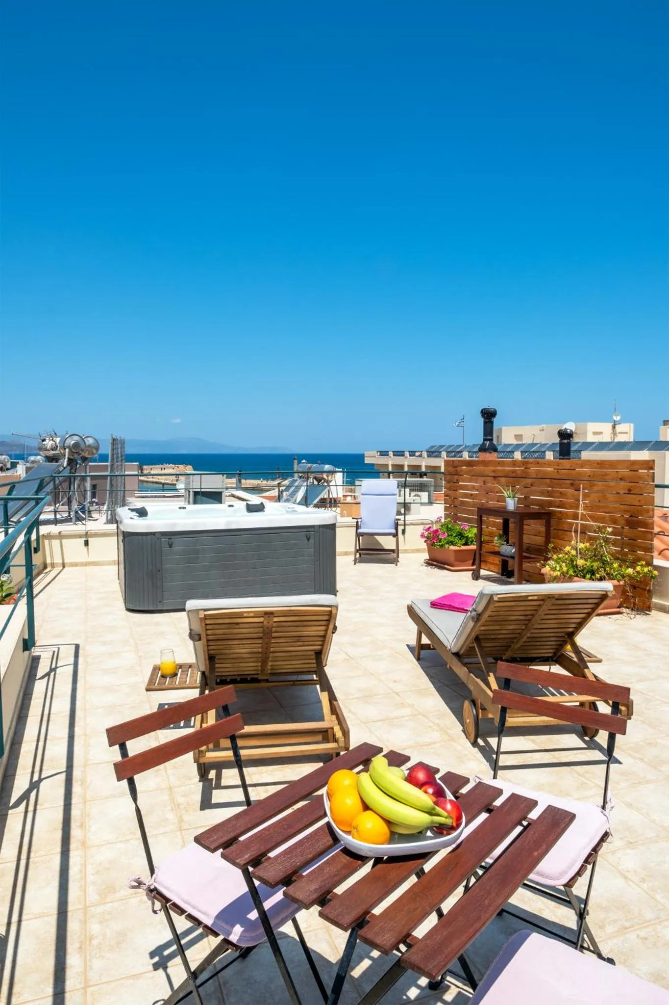 Terrasse aménagée avec transats, table basse et jacuzzi face à la mer.