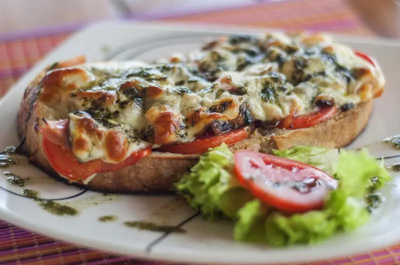 Une assiette de bruschetta garnie de légumes et de fromage, accompagnée d'une feuille de salade.