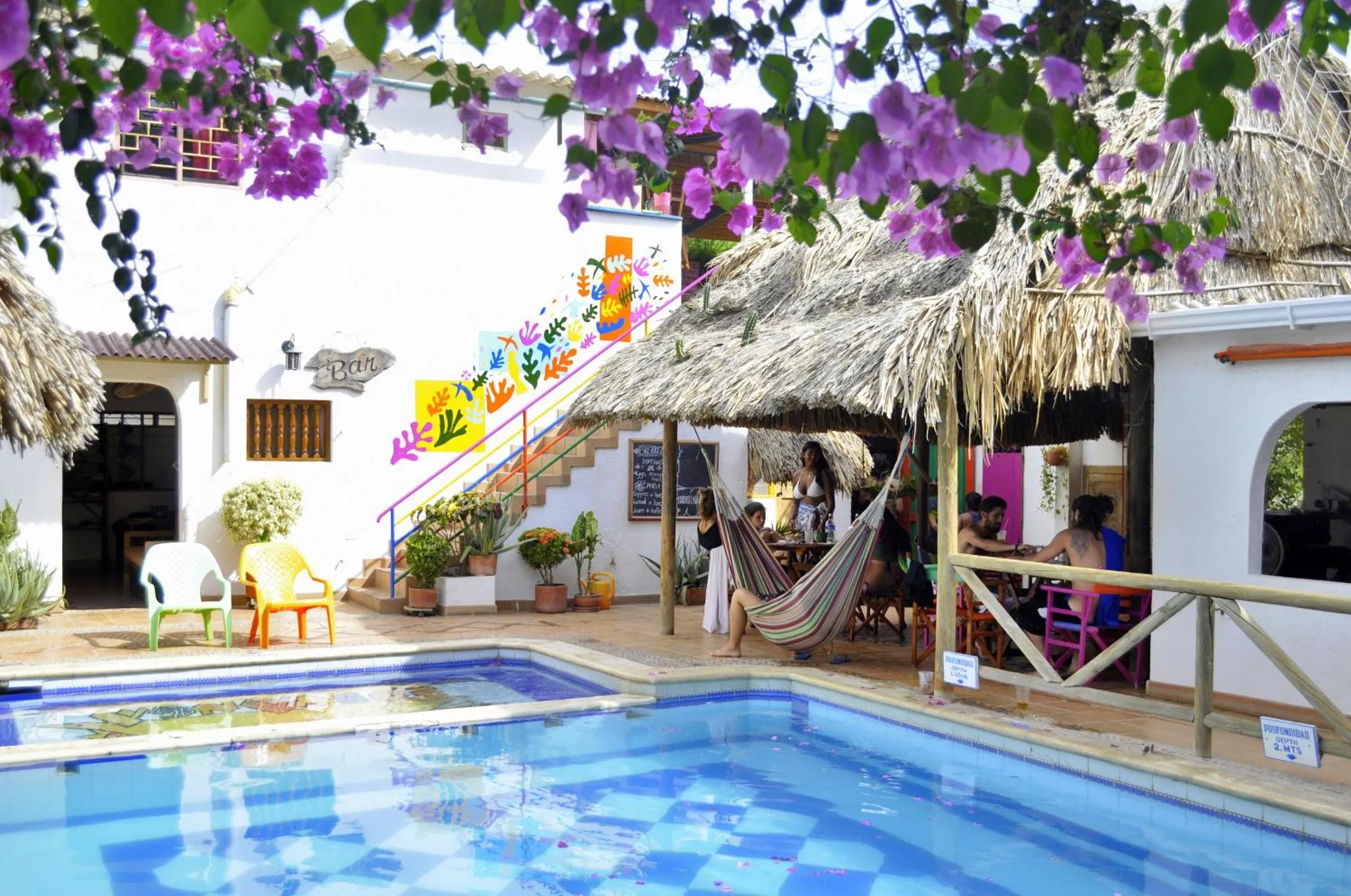 Une piscine turquoise bordée de végétation luxuriante et d'un espace détente ombragé.