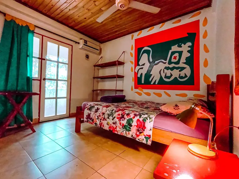 Une chambre lumineuse avec un lit recouvert d'un motif floral et une décoration murale colorée.