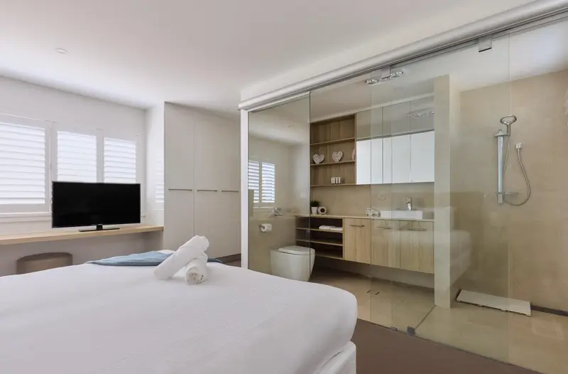 Une chambre lumineuse avec un lit et une salle de bain attenante.
