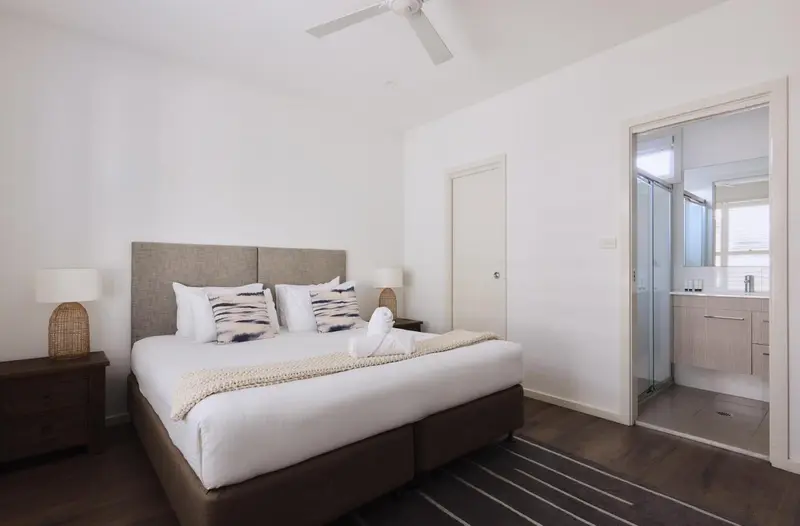 Une chambre lumineuse avec un grand lit et un accès à une salle de bain.