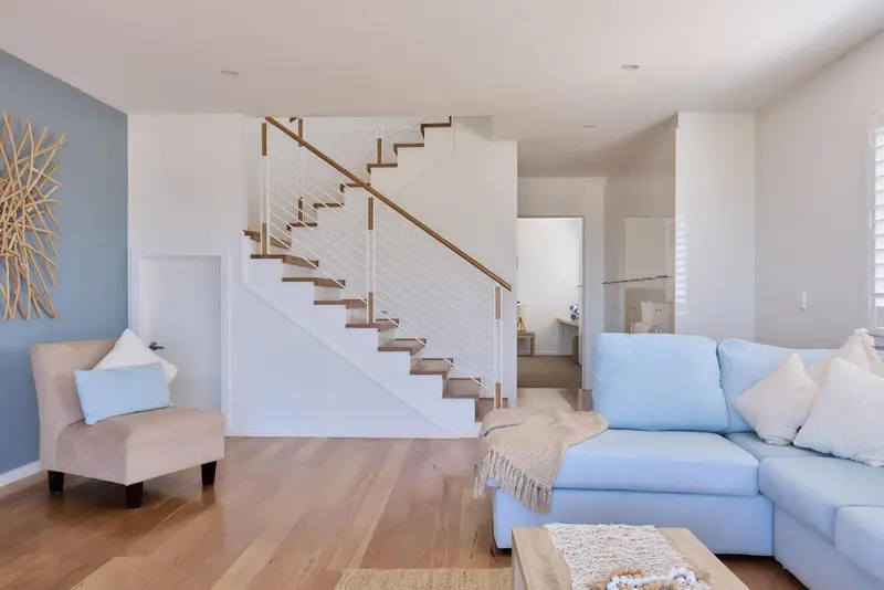 Un salon clair avec un canapé bleu et un fauteuil beige, éclairé par une fenêtre.