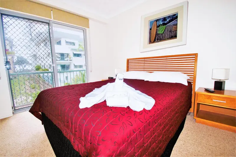 Une chambre avec un grand lit recouvert d'une courtepointe rouge et de serviettes pliées.
