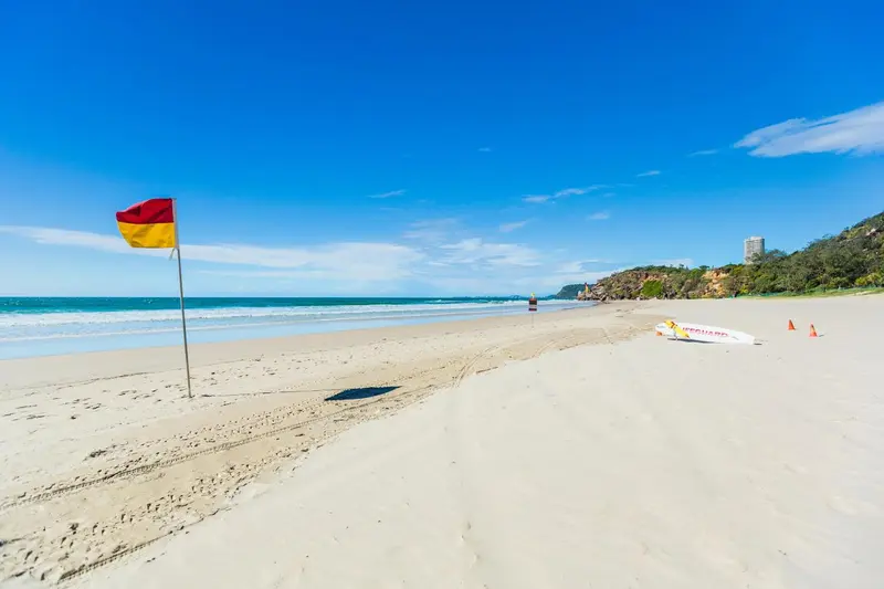 Une plage de sable fin bordée par une eau turquoise sous un ciel bleu.