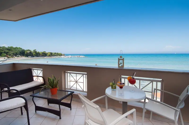 Terrasse aménagée avec salon et table donnant sur une plage de sable fin et une mer turquoise.