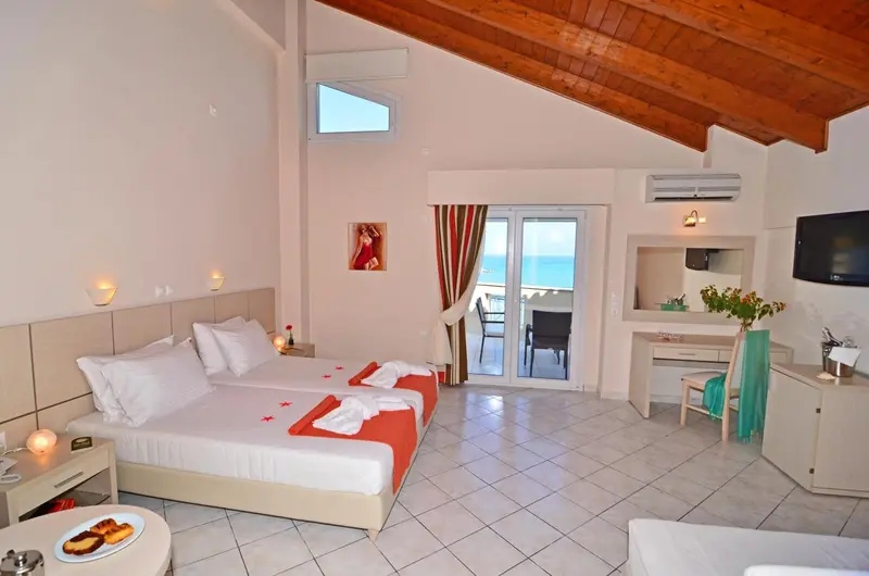 Chambre lumineuse avec un grand lit et une vue sur la mer.