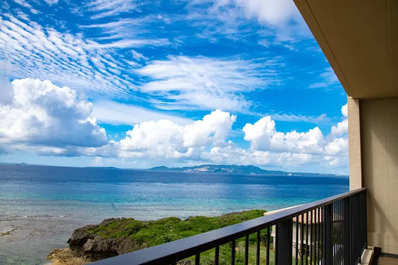 Vue sur la mer et le ciel nuageux depuis un balcon.