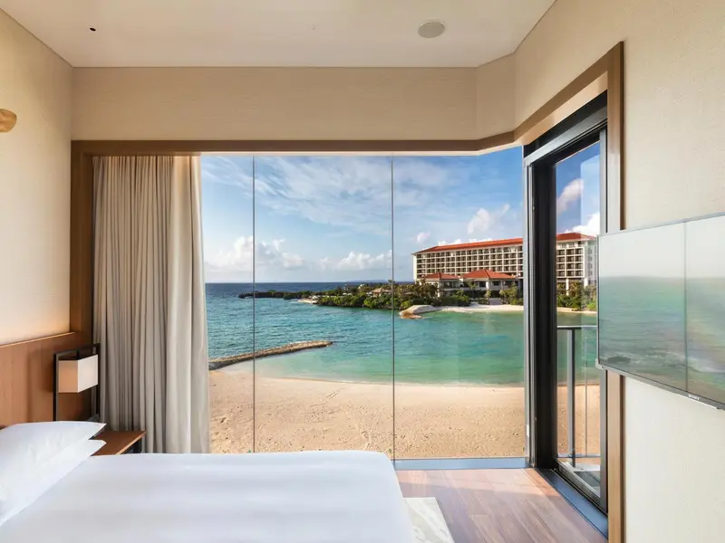 Une chambre lumineuse donne sur une plage de sable fin et une mer turquoise.