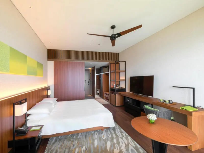 Une chambre lumineuse avec un grand lit et un espace bureau.