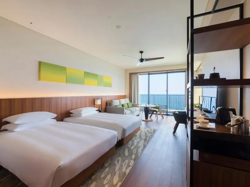Une chambre lumineuse avec un grand lit et un coin salon donnant sur l'océan.