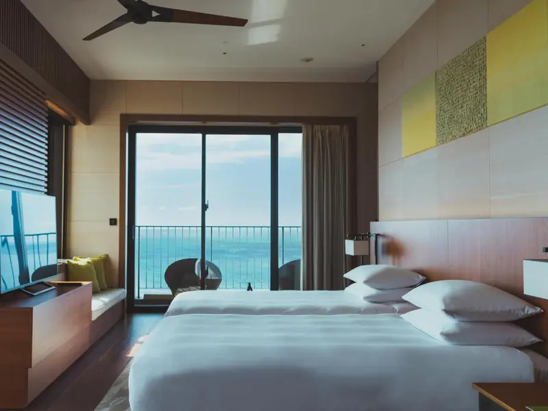 Chambre lumineuse avec un grand lit et une vue sur la mer.