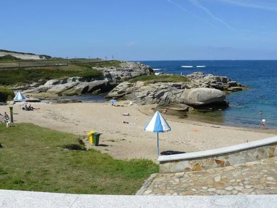 Une plage de sable avec des parasols et des personnes se relaxant au soleil.