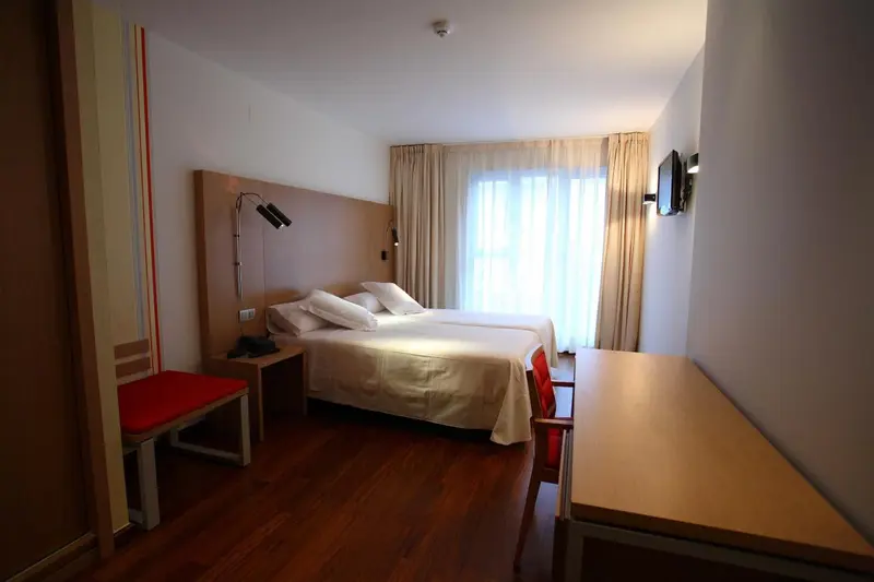 Une chambre d'hôtel lumineuse avec un lit double et un bureau.