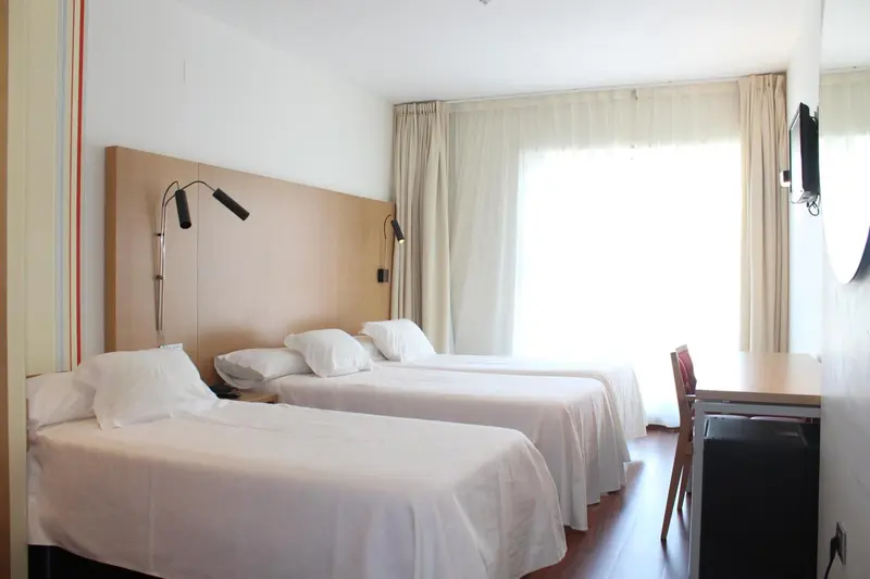 Une chambre lumineuse avec deux lits simples et un bureau.