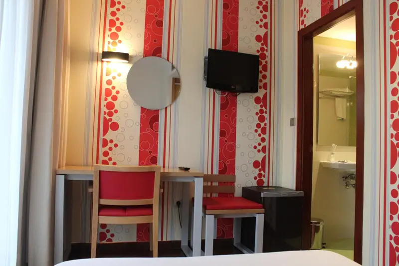 Une coiffeuse rouge et une chaise sont placées contre un mur à motifs.