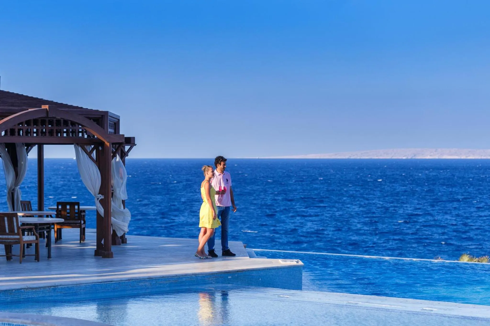 Un couple se tient sur une terrasse surplombant la mer.